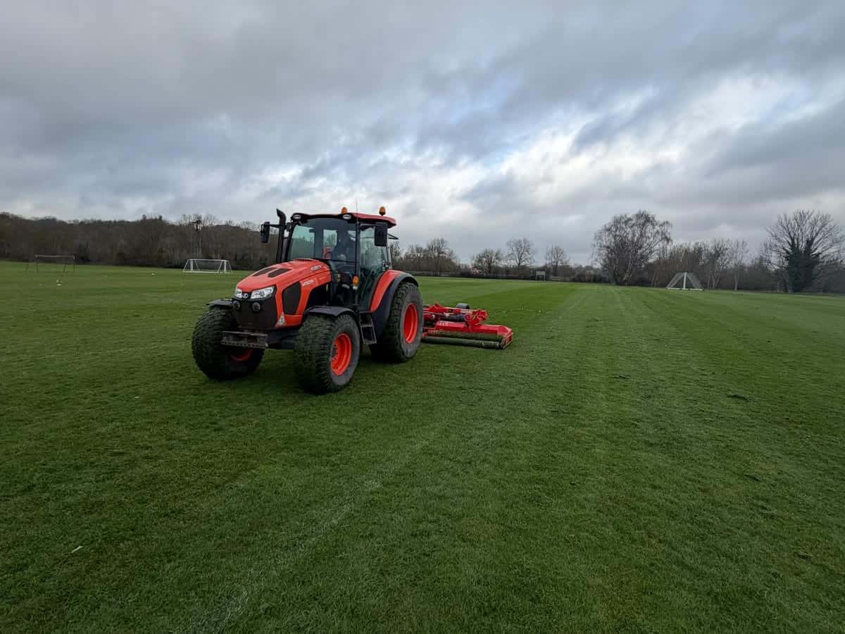 Tractor and mower cutting a playing field